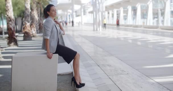 Mulher elegante sentada em um banco em um passeio — Vídeo de Stock