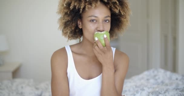 Woman sitting on bed and eating apple — Stock Video