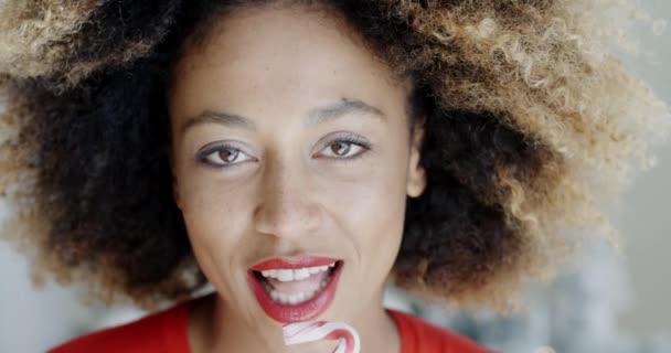 Young woman biting a festive candy cane — Stock videók