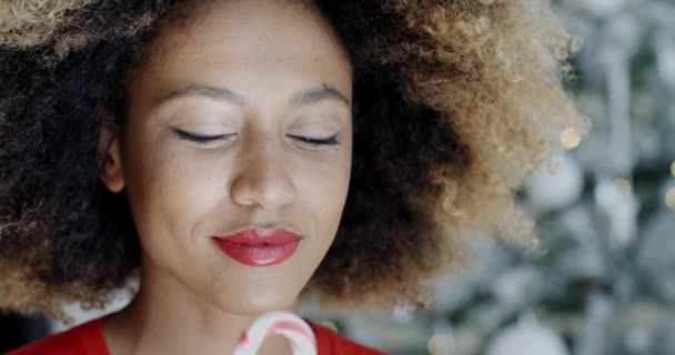 Young woman biting a festive candy cane — Stok video