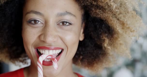 楽しい若い女性はクリスマスキャンディ杖を噛む — ストック動画