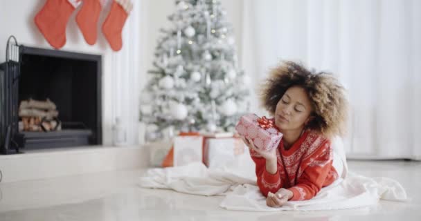 Young African girl lying looking at her Xmas gift — Wideo stockowe