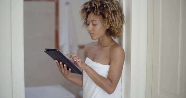 Женщина с помощью планшетного компьютера в ванной комнате — стоковое видео