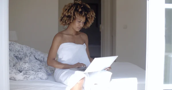 Woman with laptop computer sitting on bed — Stock Fotó