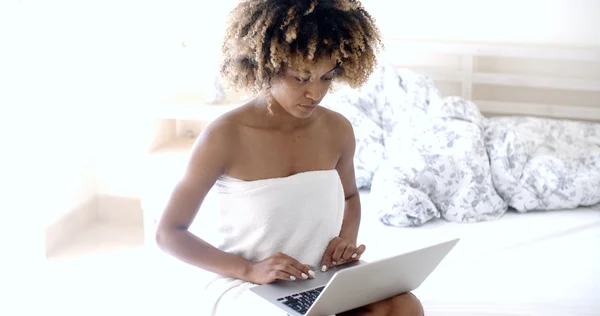 Frau mit Laptop auf Bett sitzend — Stockfoto