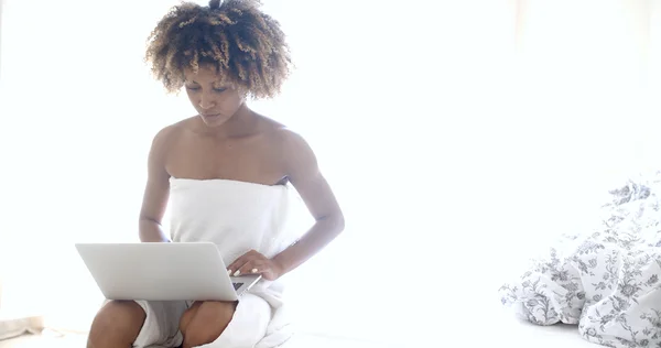 Mujer con ordenador portátil sentado en la cama — Foto de Stock