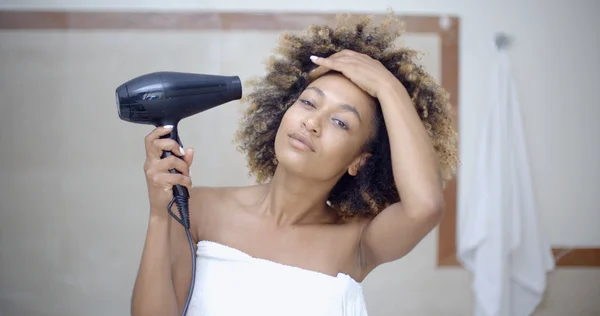 Woman holding hairdryer and drying hair — Stock Photo, Image