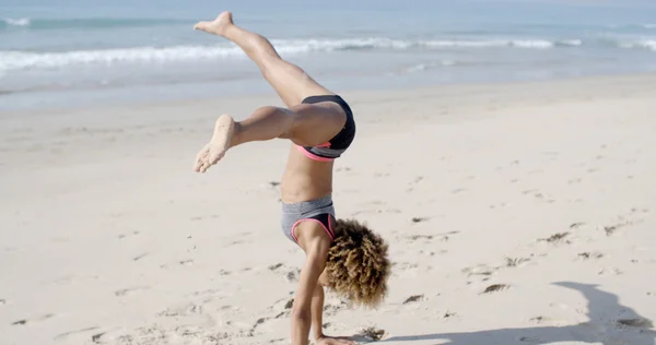 Vrouw doen waterrad op strand — Stockfoto