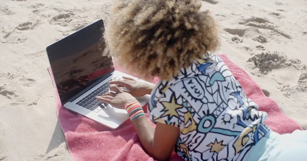 Mädchen liegt mit Laptop am Strand — Stockfoto