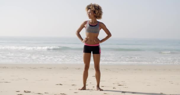 Frau trägt Sportbekleidung und steht am Strand — Stockvideo