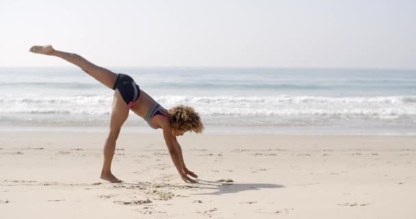 Vrouw doen waterrad op strand — Stockvideo