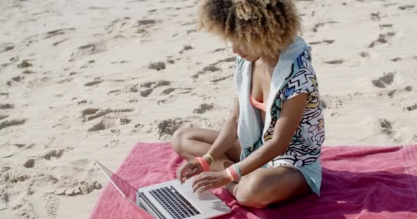 Frau sitzt auf Handtuch mit Laptop am Strand — Stockvideo