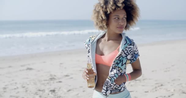 Женщина держит бутылку на берегу моря — стоковое видео