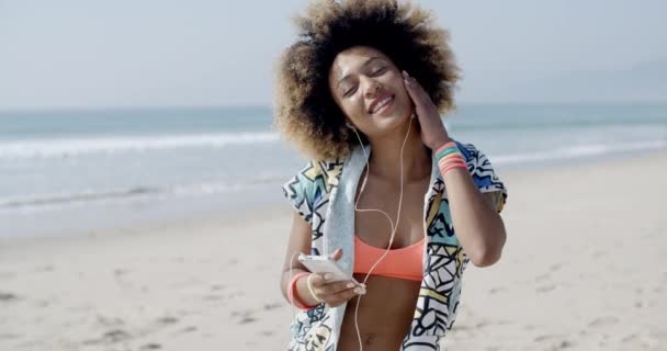 Vrouw luisteren naar muziek op koptelefoon op strand — Stockvideo