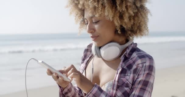 Meisje luisteren naar muziek op strand — Stockvideo