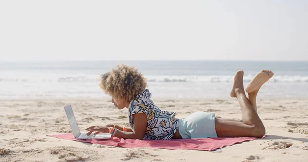 Жінка друкує на ноутбуці на пляжі — стокове фото