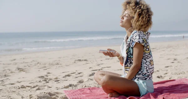 Mujer escuchando música en auriculares en la playa — Foto de Stock