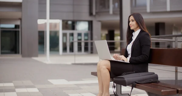 Mujer de negocios que trabaja en el ordenador portátil en el banco al aire libre — Foto de Stock