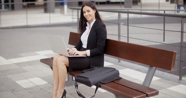 Empresária trabalhando no laptop no banco ao ar livre — Fotografia de Stock