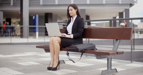 Mujer de negocios que trabaja en el ordenador portátil en el banco al aire libre — Foto de Stock