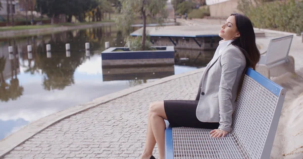 Businesswoman sitting on bench near canal — Stock Photo, Image