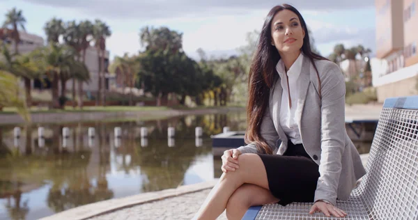 Businesswoman sitting on bench near canal — Stock Photo, Image