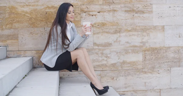 Businesswoman sitting on stairs and drinking coffee — Stock Photo, Image