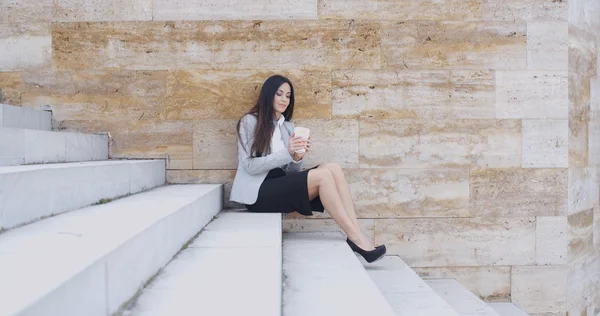 Businesswoman sitting on stairs and drinking coffee — Stock Photo, Image
