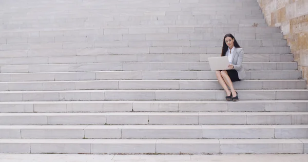 Femme d'affaires assise sur un escalier en marbre avec ordinateur portable — Photo