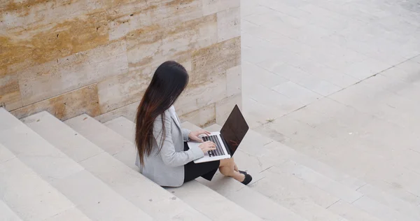 Geschäftsfrau sitzt mit Laptop auf Marmortreppe — Stockfoto