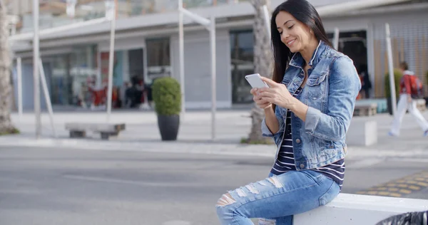 Woman in denim outfit using mobile — Stok fotoğraf