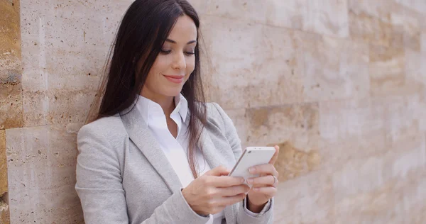 Businesswoman leaning wall and using phone — Stockfoto