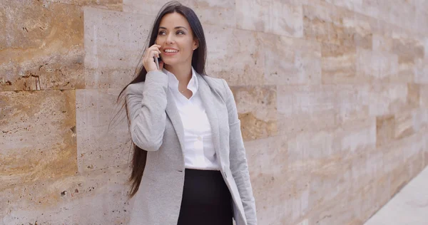 Businesswoman talking on phone and leaning on wall — 图库照片