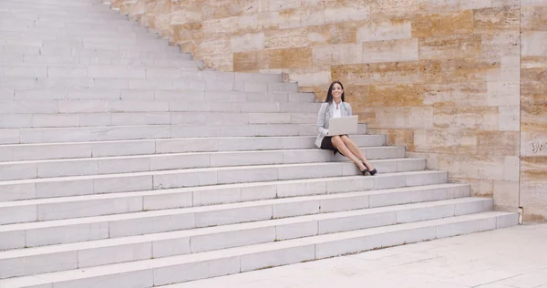 Businesswoman sitting on marble staircase with laptop — Stock Photo, Image