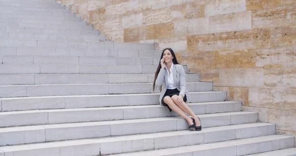 Businesswoman on marble stairs talking on phone — ストック写真