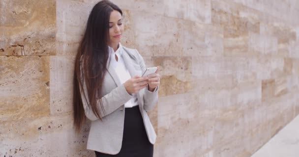 Бізнес-леді спираючись на стіну і використовуючи телефон — стокове відео