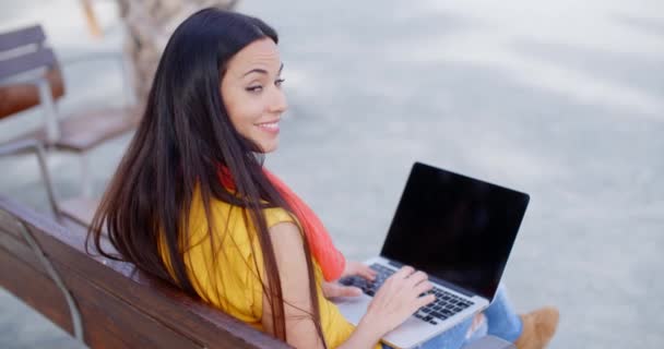 Žena sedí na lavičce a pracuje na notebooku — Stock video