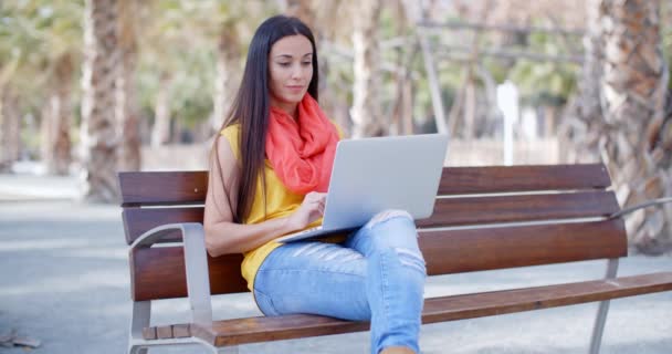 Femme assise sur un banc et travaillant sur un ordinateur portable — Video