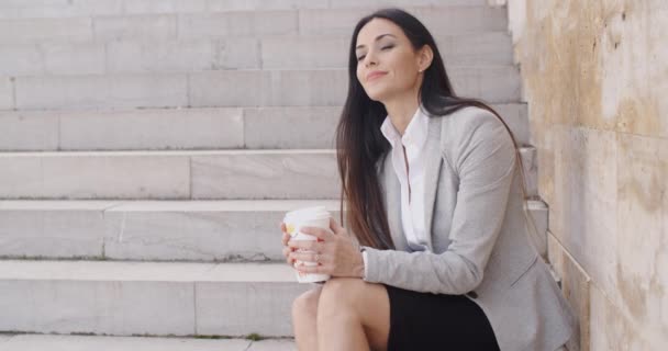 Businesswoman sitting on stairs and drinking coffee — Stock Video