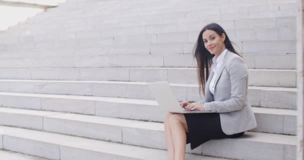 Mujer de negocios sentada en una escalera de mármol con portátil — Vídeos de Stock