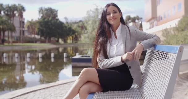 Business woman sitting on bench near canal — стоковое видео