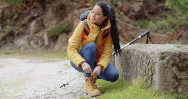 Woman tying laces on mountain trail — ストック動画