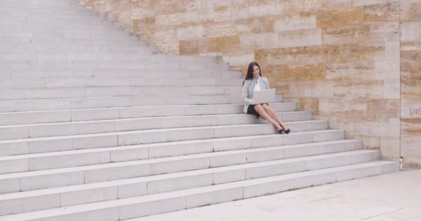 Mujer de negocios sentada en una escalera de mármol con portátil — Vídeo de stock