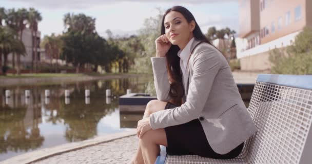 Бізнес-леді сидить на лавці біля каналу — стокове відео