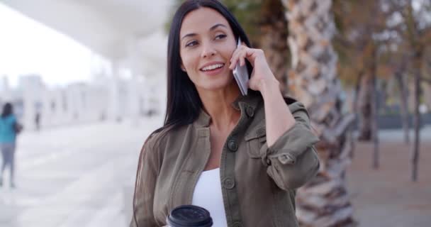 Женщина, идущая в парк и разговаривающая по мобильному телефону — стоковое видео