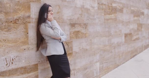 Businesswoman talking on phone and leaning on wall — 图库视频影像