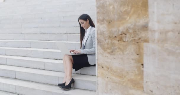 Mujer de negocios sentada en una escalera de mármol con portátil — Vídeos de Stock