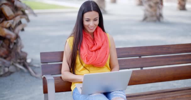 Kvinna sitter på bänken och arbetar på laptop — Stockvideo