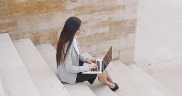 Mujer de negocios sentada en una escalera de mármol con portátil — Vídeos de Stock