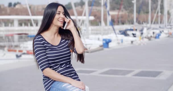 Mujer sentada en el muelle y hablando en móvil — Vídeo de stock